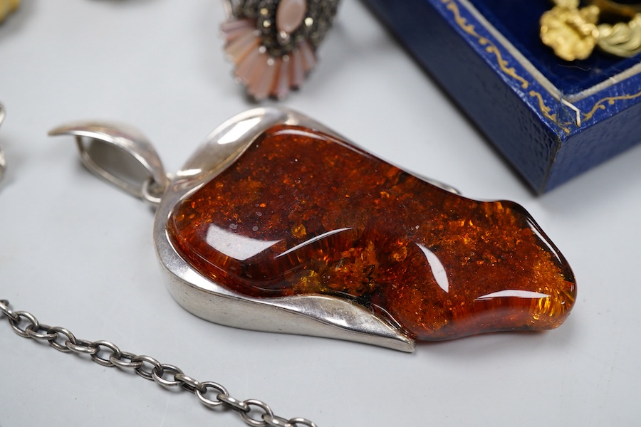 A collection of jewels, comprising: two amber pendants and an amber ring, each mounted in silver; a pair of gilt metal and enamel earrings of floral design; a pair of gilt metal earrings; a silver and cultured brooch; a